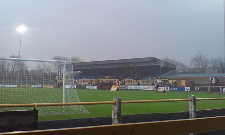 view from behind the goal at Gander Green lane, home of Sutton Utd. View shows goal, pitch and stand to the right of the goal.